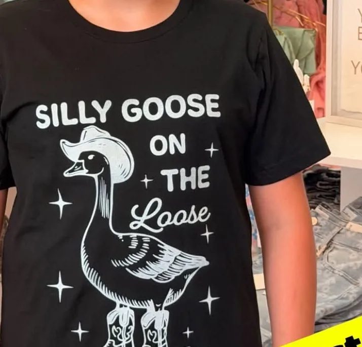Black tee printed in white with a goose wearing a cowboy hat and boots, reading Silly Goose On The Loose.